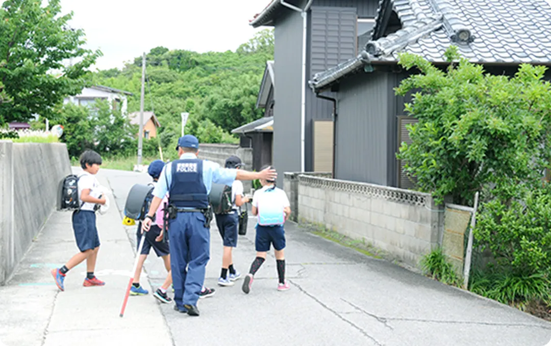 道端で小学生と話す警察官の後ろ姿