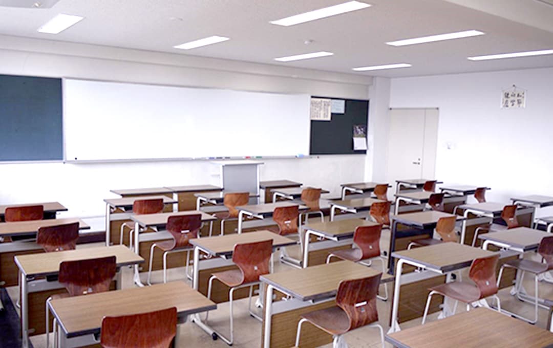 ホワイトボードと椅子・机が並んだ教室の画像